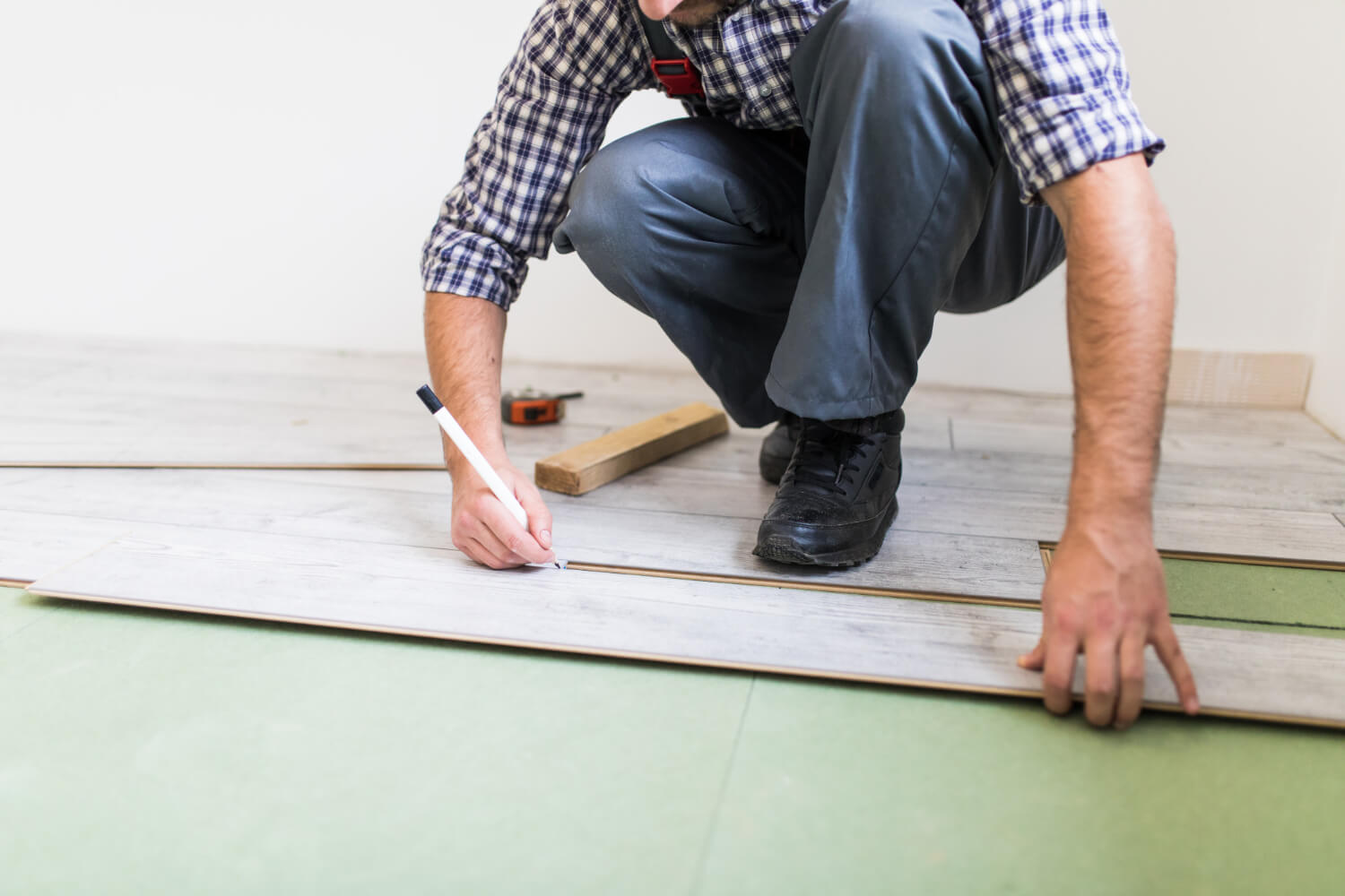 Handwerker verlegt Laminatboden mit Trittschalldämmung